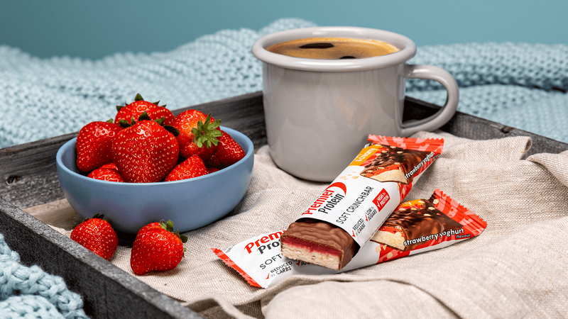 Bowl of strawberries, mug of coffee, and Proctor & Gamble strawberry-flavored chocolate bars on a tray.