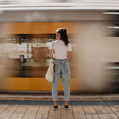 Woman waiting on a train platform with a blurred train in the background