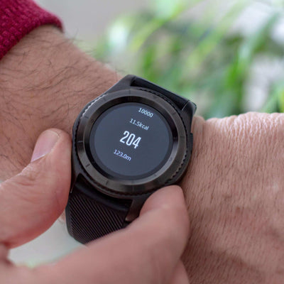 Person wearing a black smartwatch with digital display on a blurred background