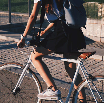 Person riding a bicycle on a paved road with a backpack