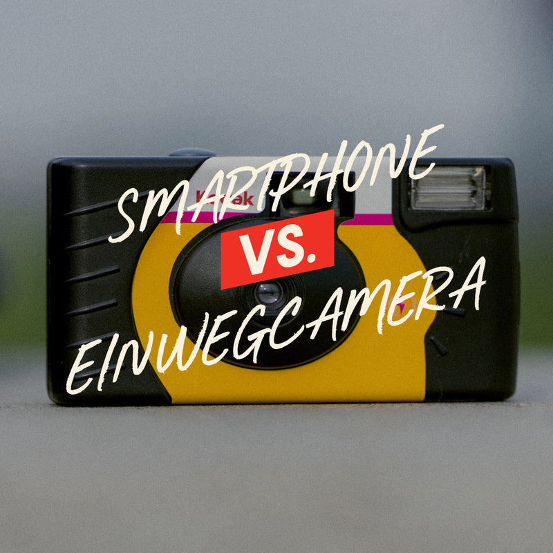 Film camera with text 'Smartphone vs. Einwegkamera' on a gray background