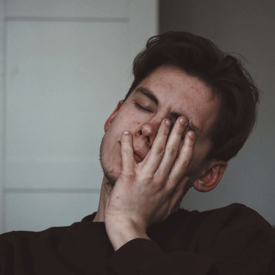 Man with hand over mouth in a neutral setting