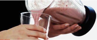 Person pouring a pink smoothie from a blender into a glass.
